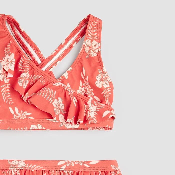 Close-up of raspberry hibiscus bikini top showing frilly straps and crossover detail on girls swimwear.