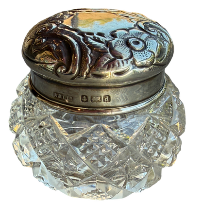 Decorative glass jar with silver lid on a white background