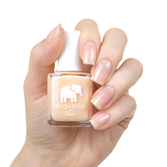 Bare sheer nude tint nail polish manicure on a light skin tone with the bottle