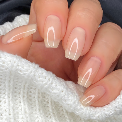 Bare sheer nude nail polish close-up on a light skin tone with a white sweater