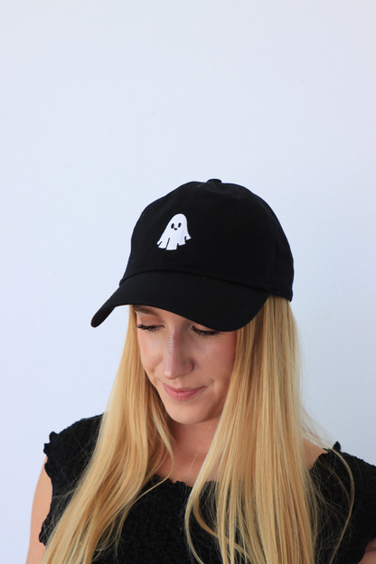 Person wearing a black cap with a white ghost design on a light blue background