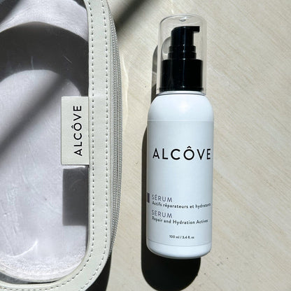 A lifestyle image of the Alcove Hair Serum 100 ml / 3.4 oz next to a Alcxove pouch