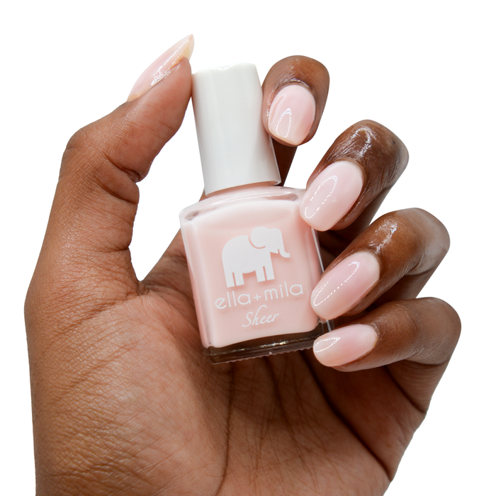 Dream sheer baby pink nail polish on a deep skin tone, hand holding the bottle