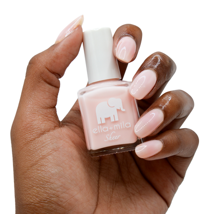 Dream sheer baby pink nail polish on a deep skin tone, hand holding the bottle