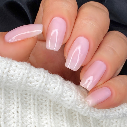 Dream sheer baby pink nail polish close-up on a light skin tone with a white sweater