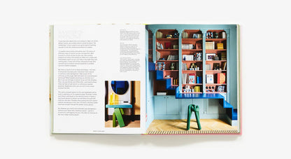 Open book showing a colorful interior design with shelves and furniture.