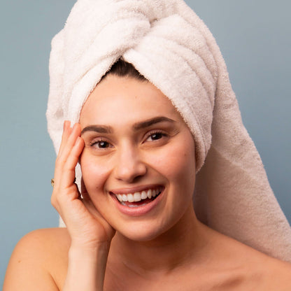 woman wearing a towel wrapped around head and hand on cheek.