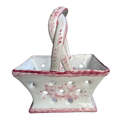 White ceramic basket with pink floral patterns and matching spoon on a white background
