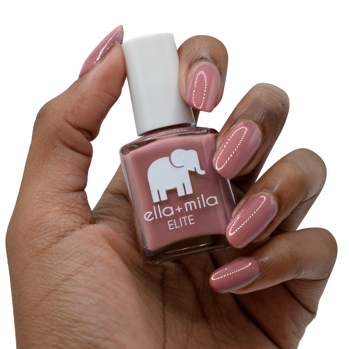 Wanderer brown brick red nail polish on a deep skin tone, hand holding the bottle