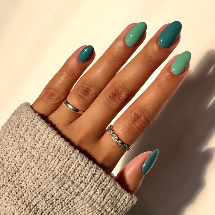 Window Seat grey blue and teal mix-and-match manicure with rings in sunlight
